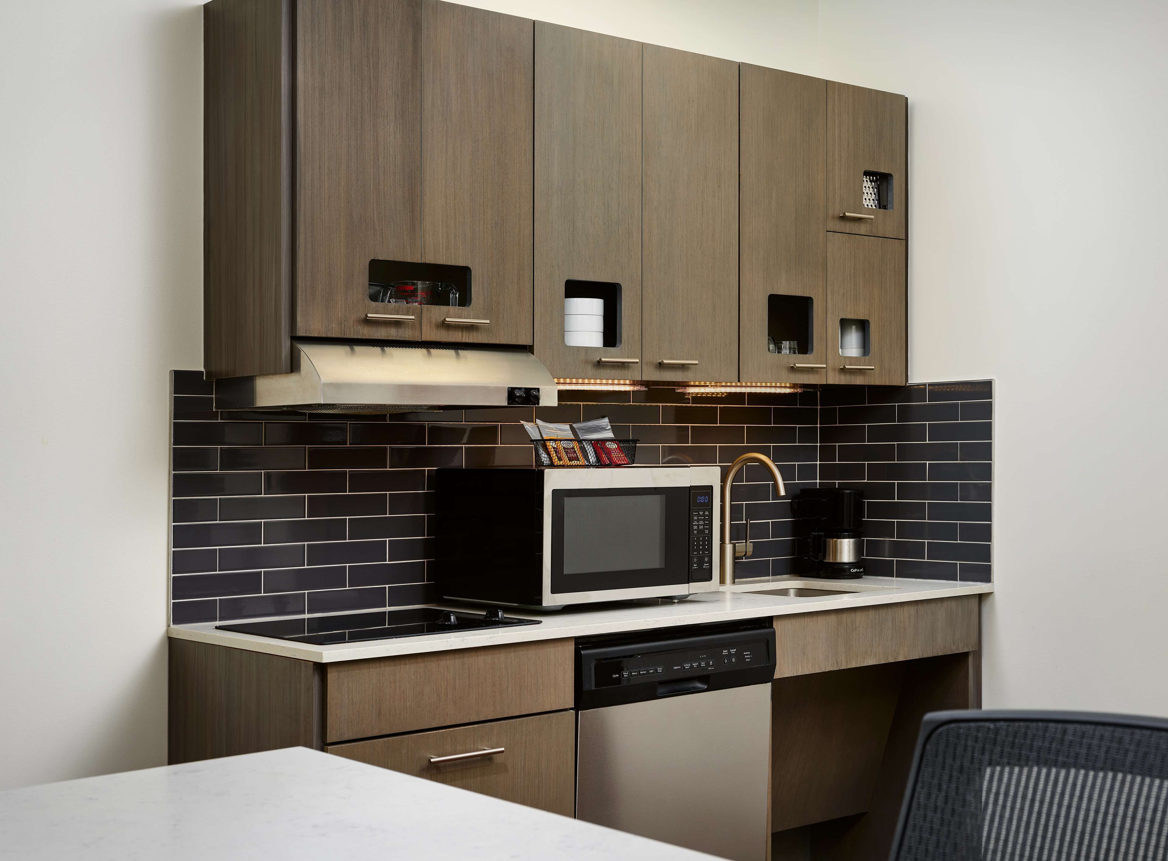 Een moderne keuken met donkerhouten kastjes, een roestvrijstalen magnetron en een vaatwasser.