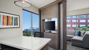 A modern hotel room with a large window, a flat-screen TV, a gray sofa, and a marble-topped desk. - Hyatt House Atlanta Downtown (Atlanta)