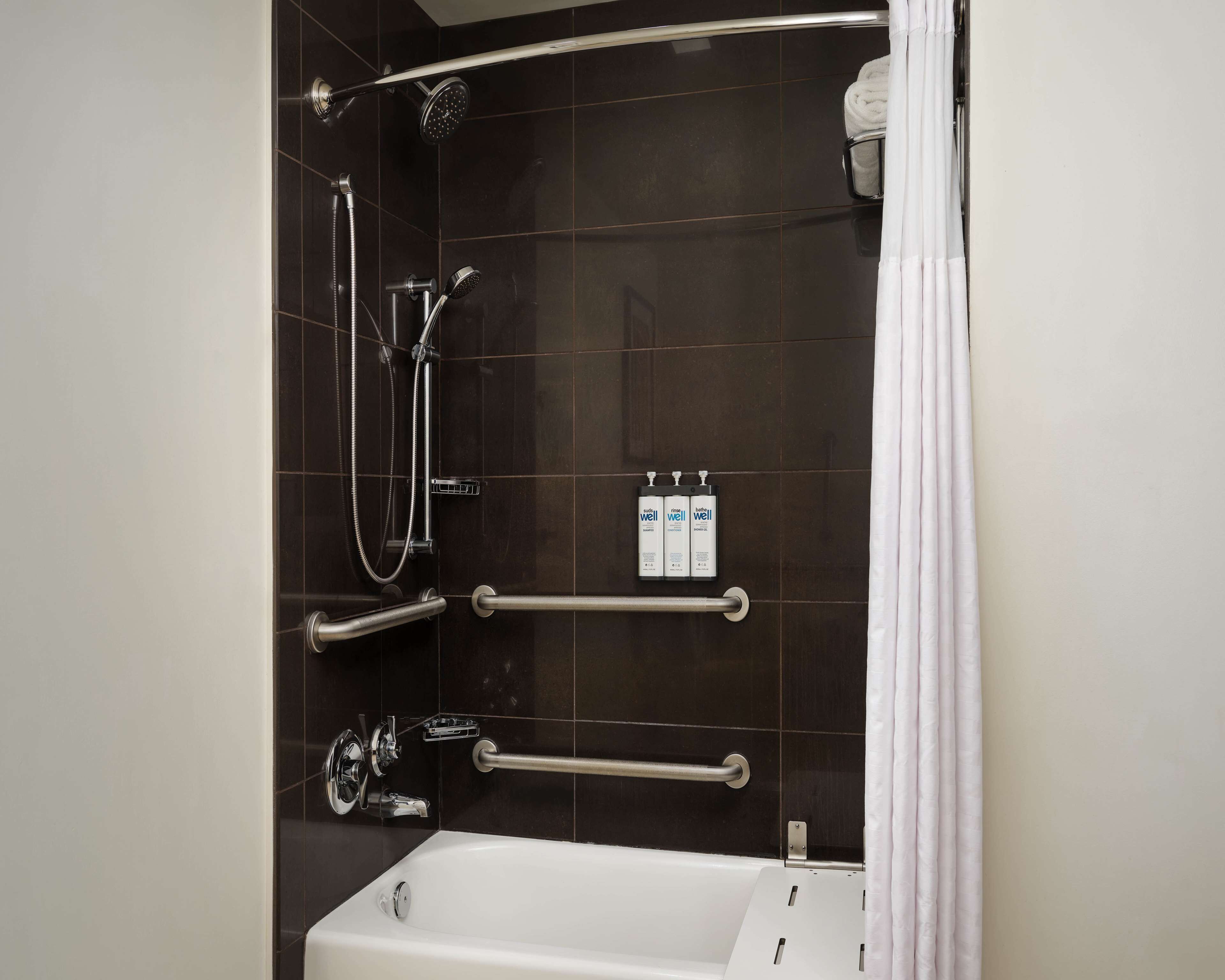Une salle de bain moderne équipée d’une baignoire, d’un espace douche et d’une barre d’appui.