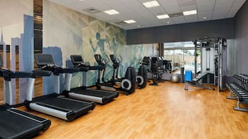 Un gimnasio con cintas de correr, elípticas y equipo de pesas.