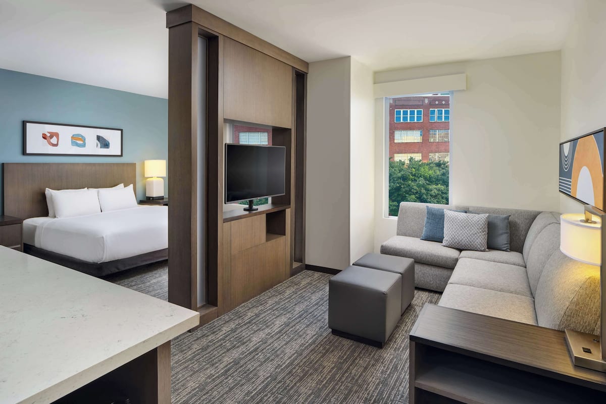 A hotel room with a bed, a TV, a sofa, and a desk.