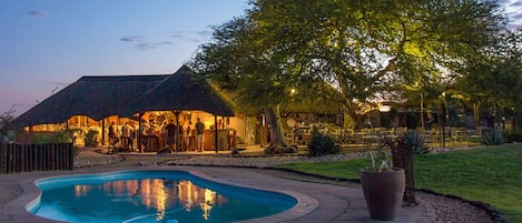 Una piscina al aire libre, sombrillas, sillones reclinables de piscina