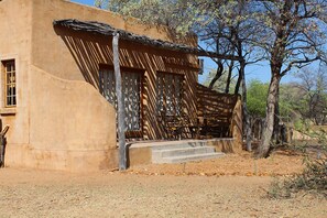 A traditional adobe building with a wooden porch and steps leading to a door. - Harnas Wildlife Foundation (Gobabis)