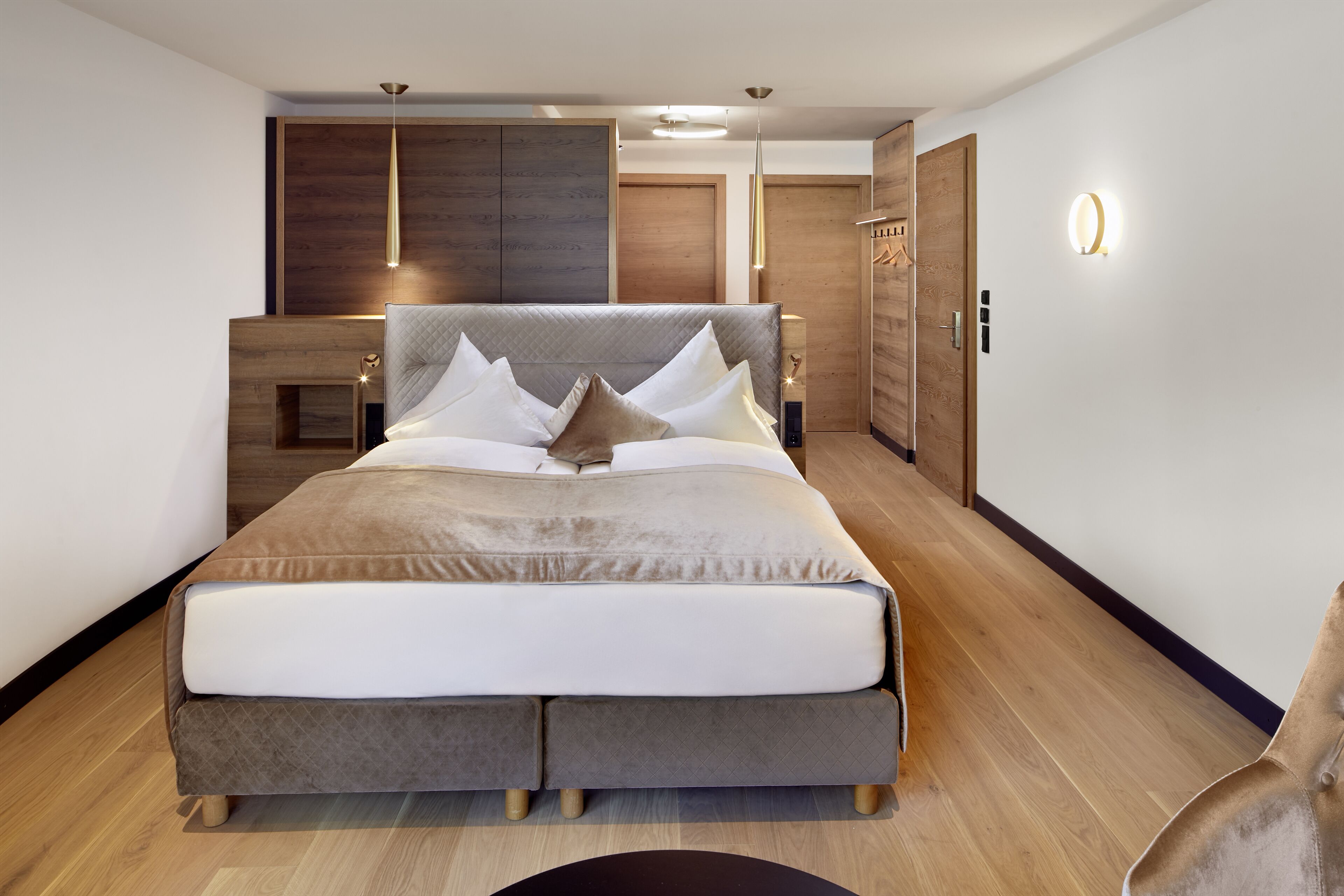 Een moderne slaapkamer met een groot bed, houten hoofdeinde en een inbouwkast.