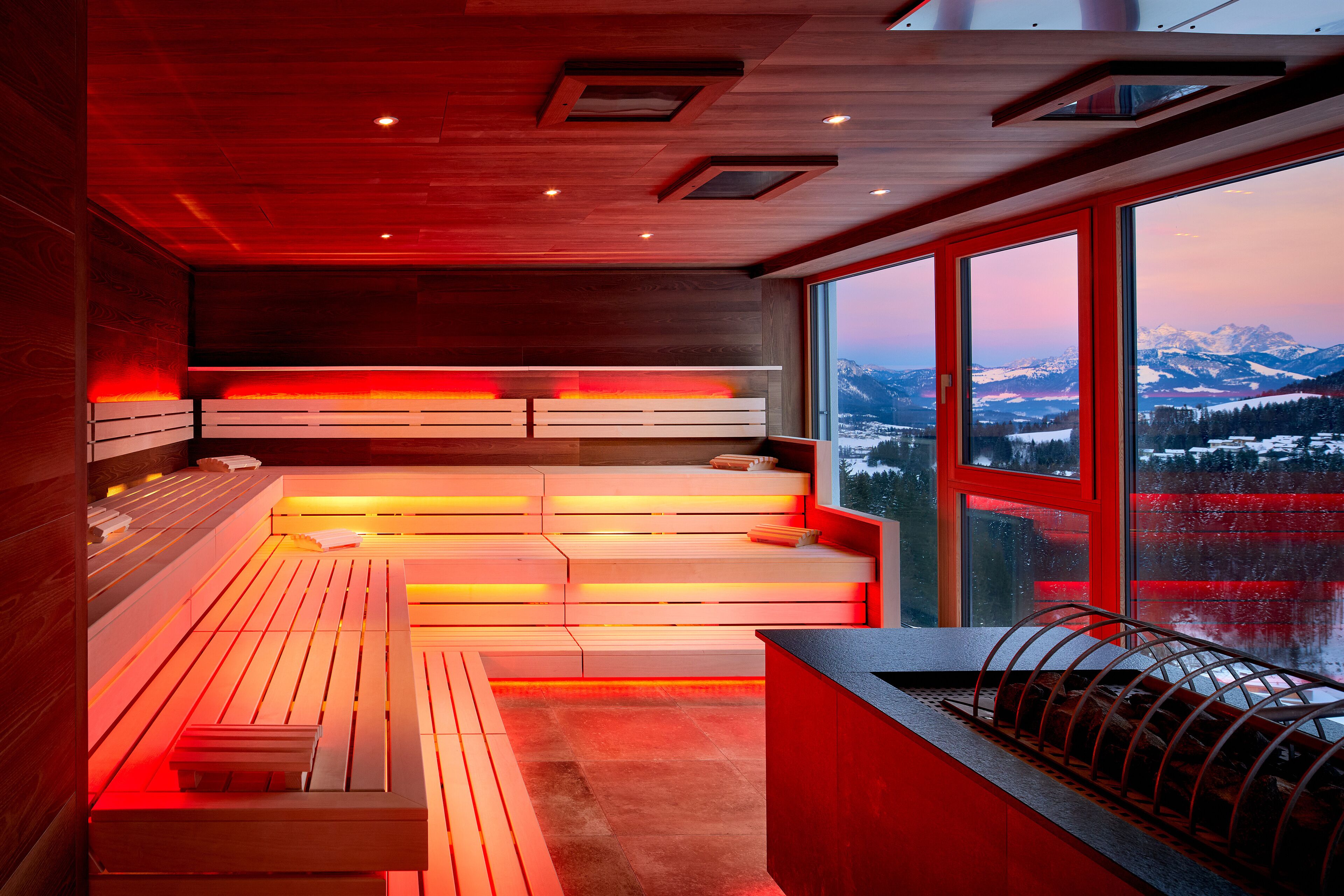 Un moderno spa con bancos de madera y un amplio ventanal con vistas a la montaña.