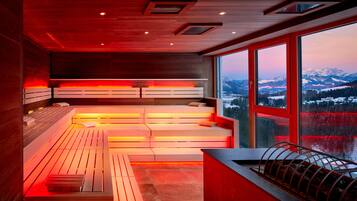 Un moderno spa con bancos de madera y un amplio ventanal con vistas a la montaña.