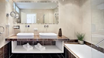 Une salle de bain moderne avec deux lavabos, un grand miroir, une baignoire et une douche.