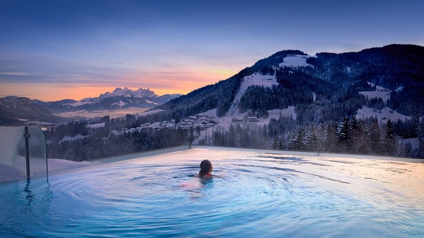 A person in a pool with a mountainous landscape in the background. - Hotel Kaiserhof (Ellmau)