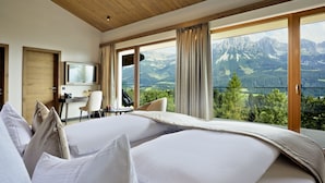 A hotel room with a large bed, a desk, and a view of mountains. - Hotel Kaiserhof (Ellmau)