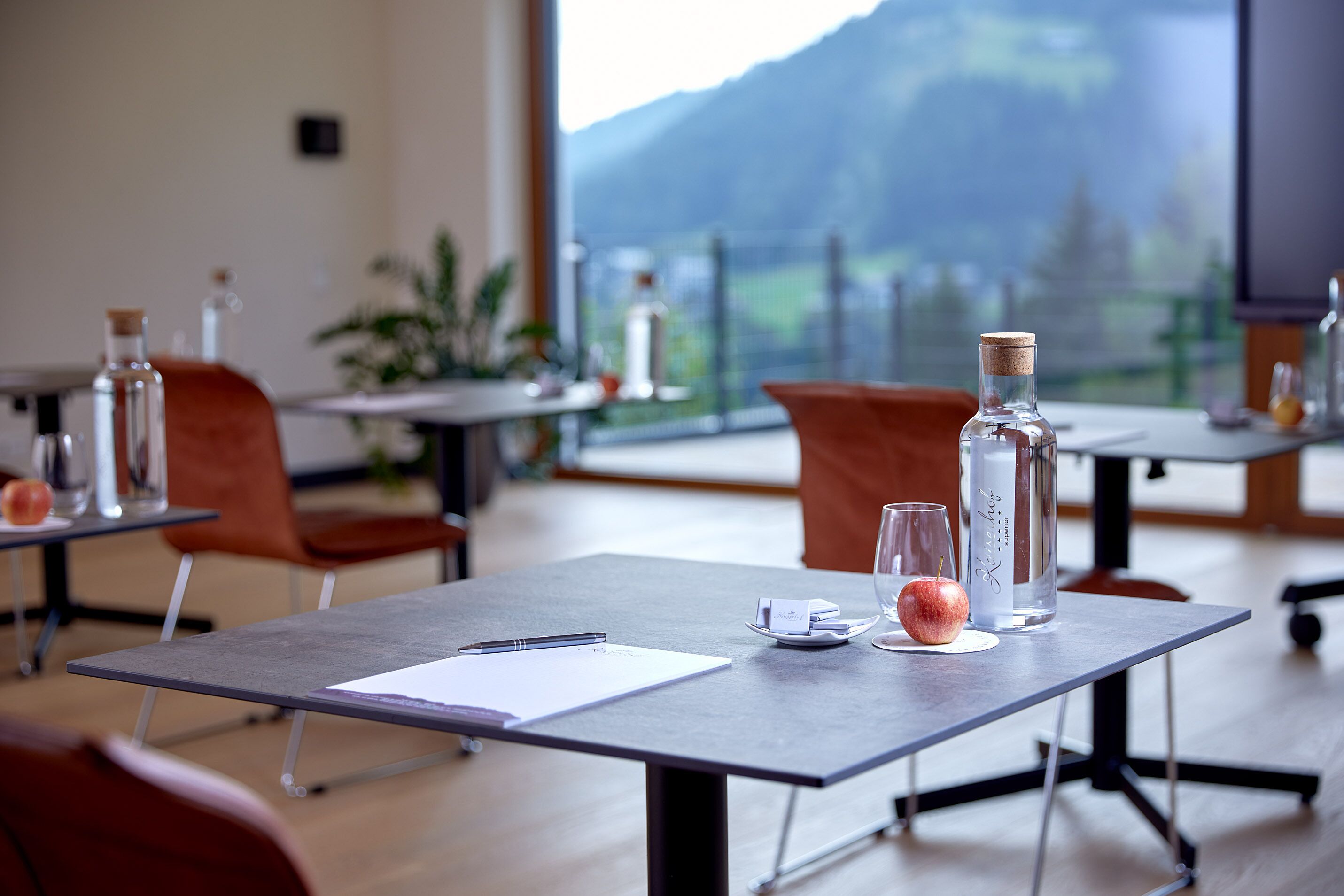 Ein moderner Essbereich mit Tischen, Stühlen und Bergblick durch große Fenster.
