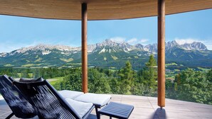 A wooden deck with lounge chairs overlooking a mountainous landscape. - Hotel Kaiserhof (Ellmau)