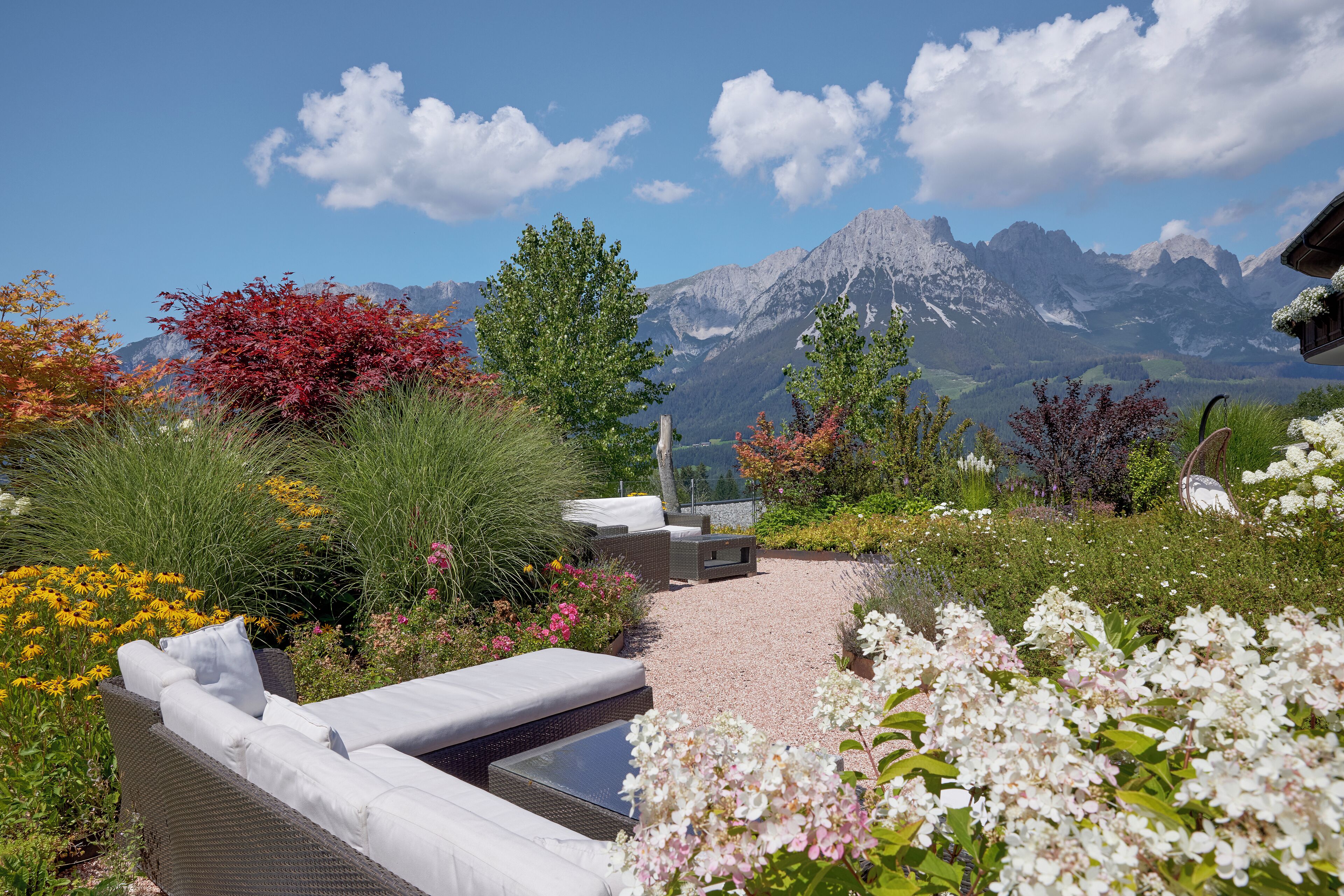 Un jardín con mobiliario exterior, una piscina y vistas a la montaña.