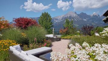 Un jardín con mobiliario exterior, una piscina y vistas a la montaña.
