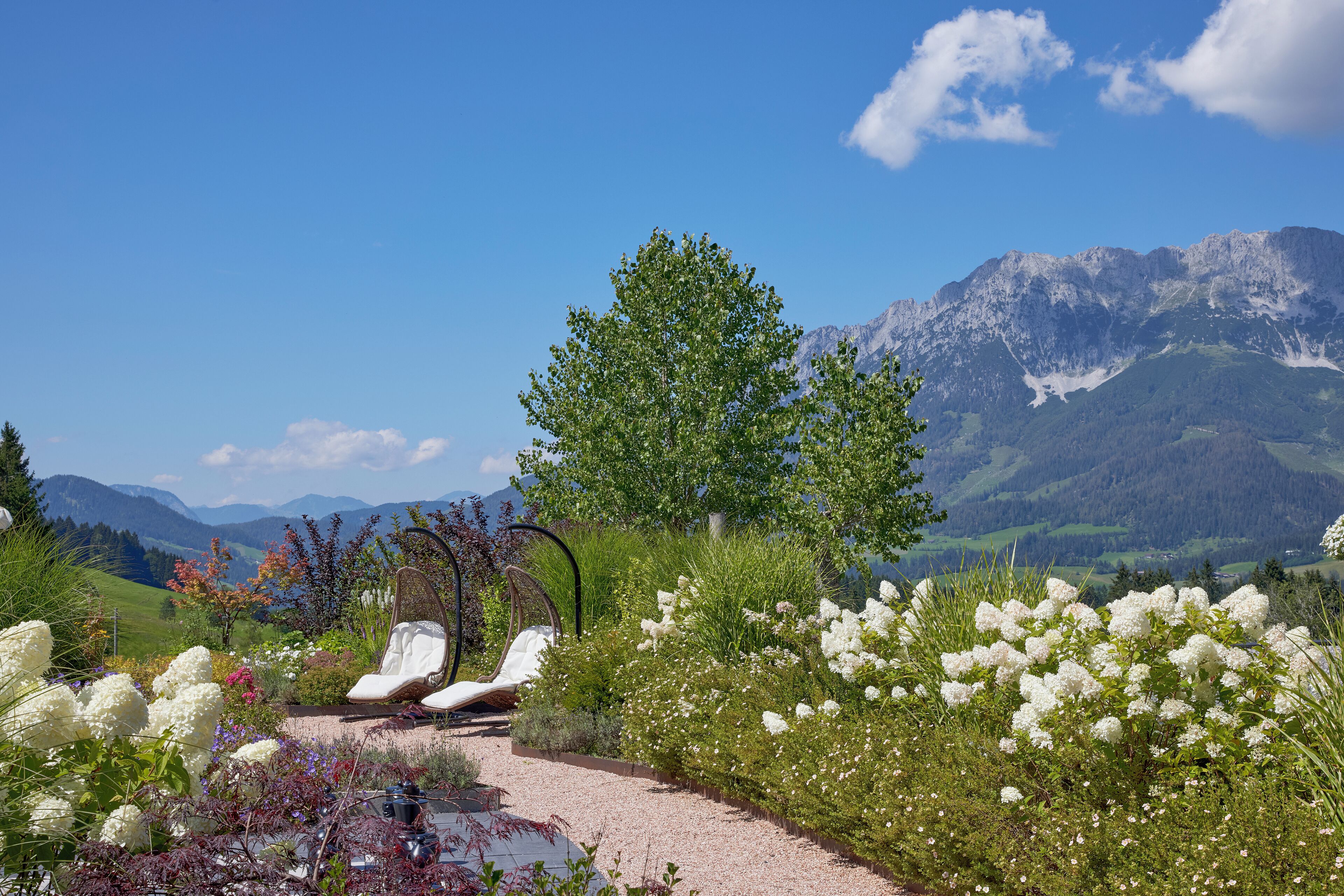 Un jardín con una zona de estar, un árbol y vistas a la montaña.