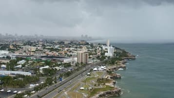 Vista aérea de una ciudad costera con un faro destacado, una zona urbana densa y una vista despejada del mar.
