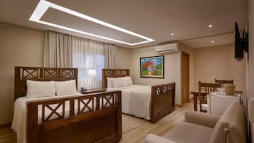 A hotel room with two wooden beds, a sofa, a desk, and a painting on the wall.
