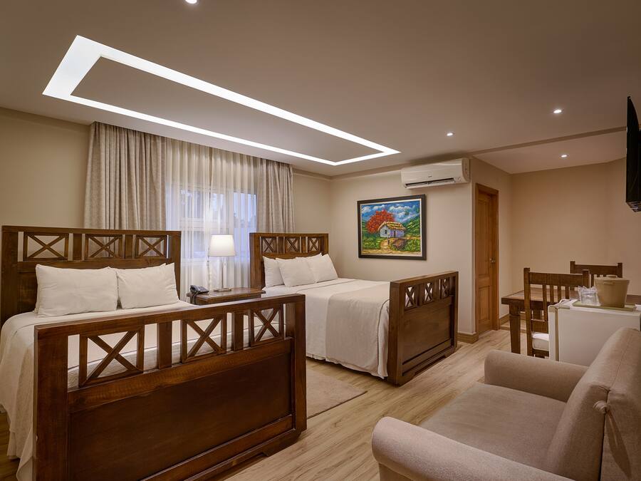 A hotel room with two wooden beds, a sofa, a desk, and a painting on the wall.