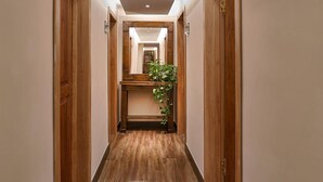 Passadís d'hotel amb portes de fusta, un banc al centre i una planta.