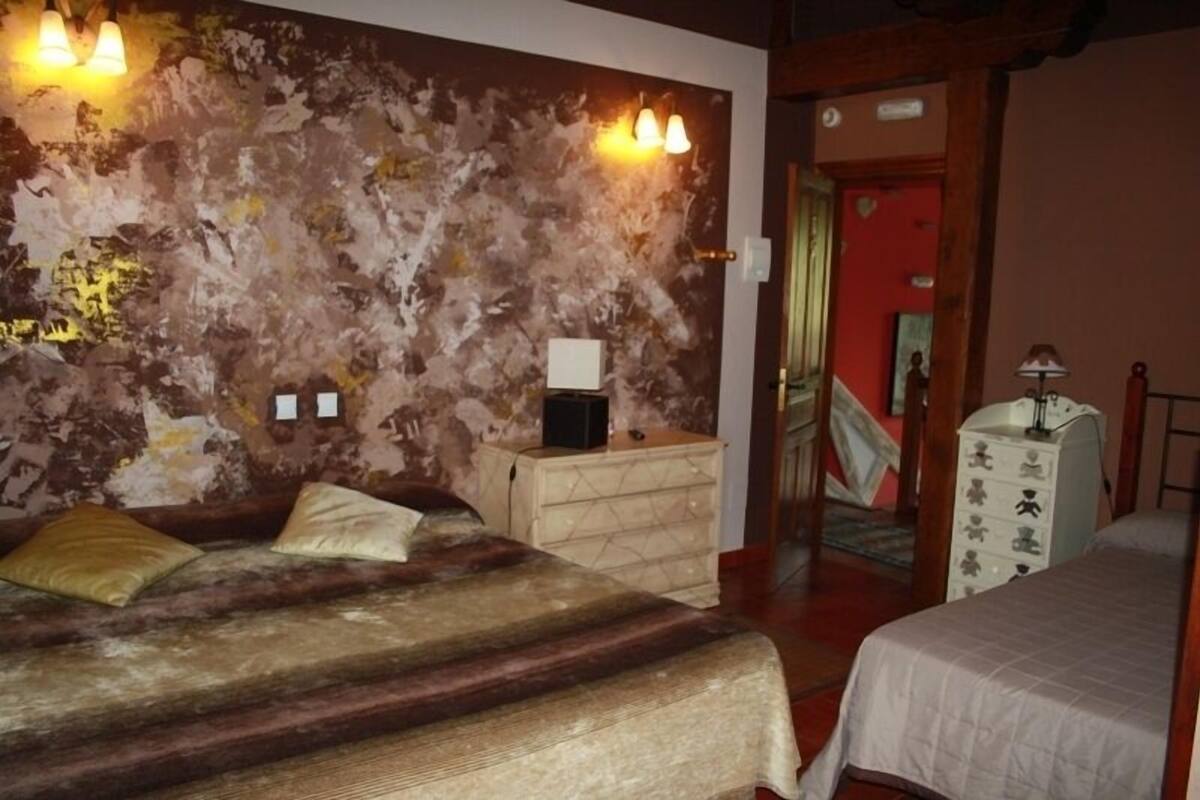 A bedroom with a bed, bedside tables, a dresser, and a wall with a textured design.