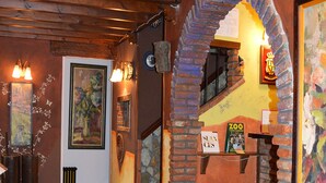 A cozy interior with a wooden ceiling, a brick archway, and a tiled floor. - Posada El Valle (Suances)