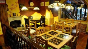 A restaurant with wooden tables and chairs, a fireplace, and decorative lamps. - Posada El Valle (Suances)