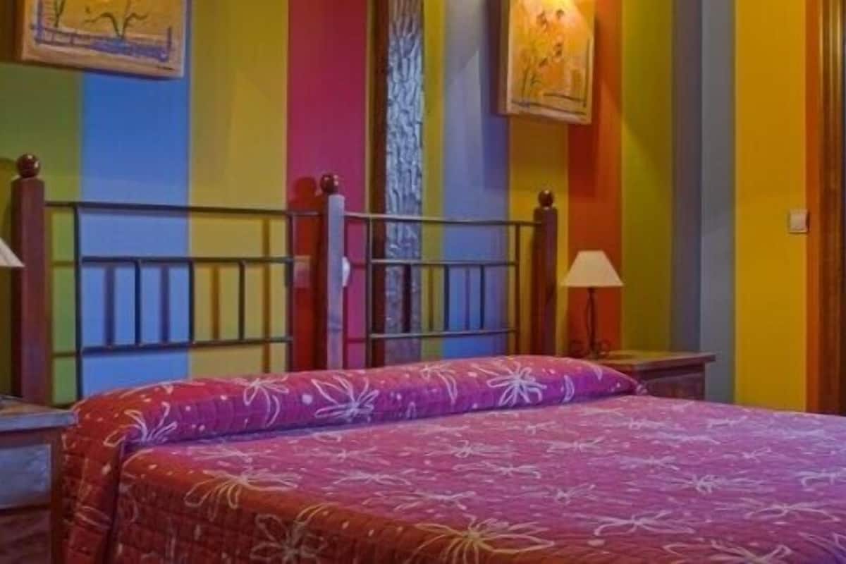 A room with a bed, two bedside tables, and a mirror.