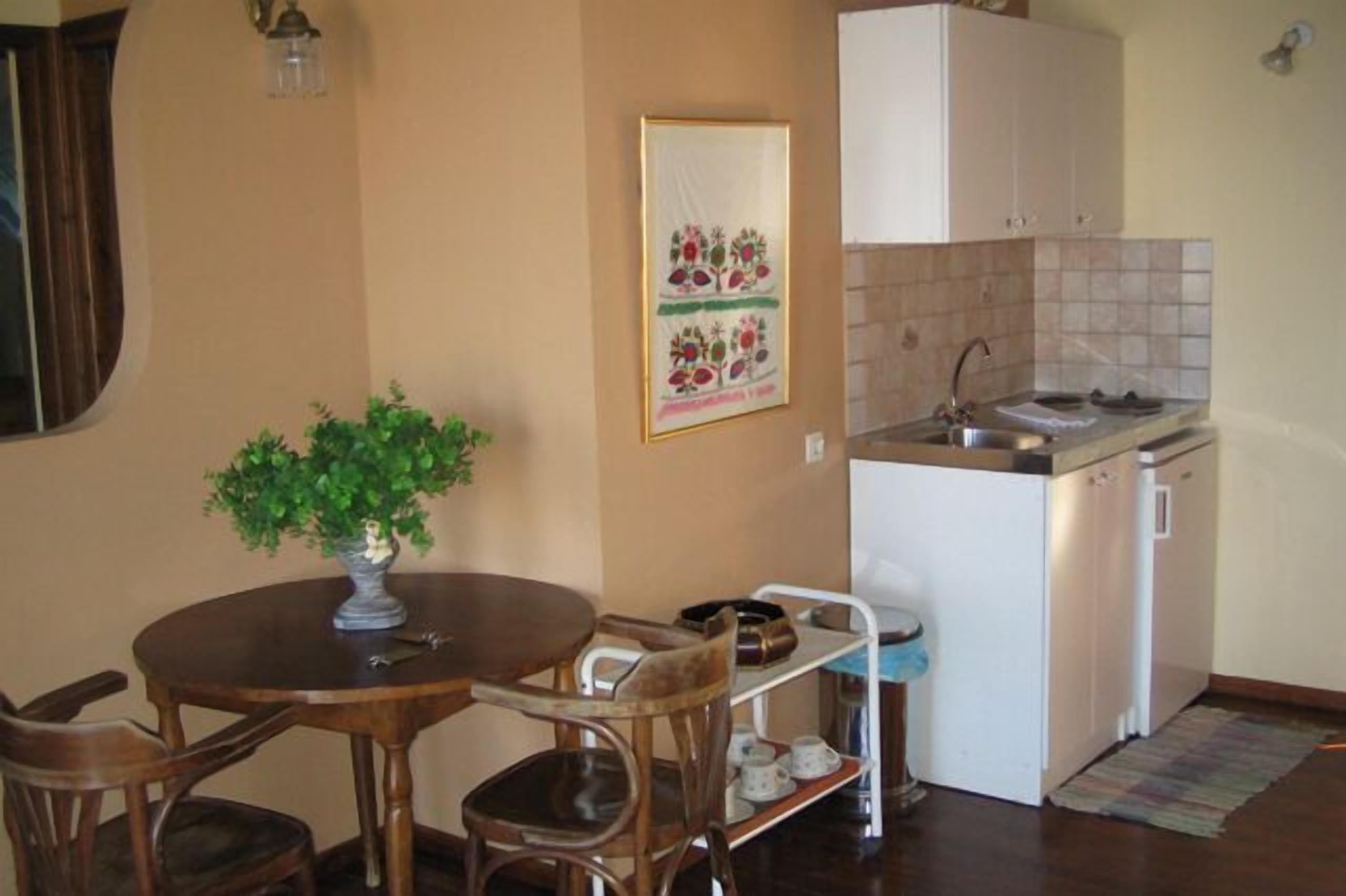 A compact kitchen with a sink, a small refrigerator, and a dining area with a table and chairs.