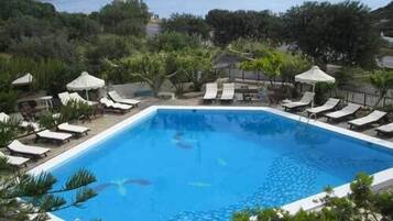 Una piscina al aire libre, sombrillas, sillones reclinables de piscina