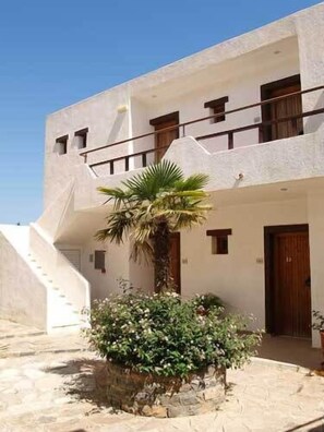 A white building with a staircase, a palm tree, and a potted plant. - Cretan Village (Agios Nikolaos)
