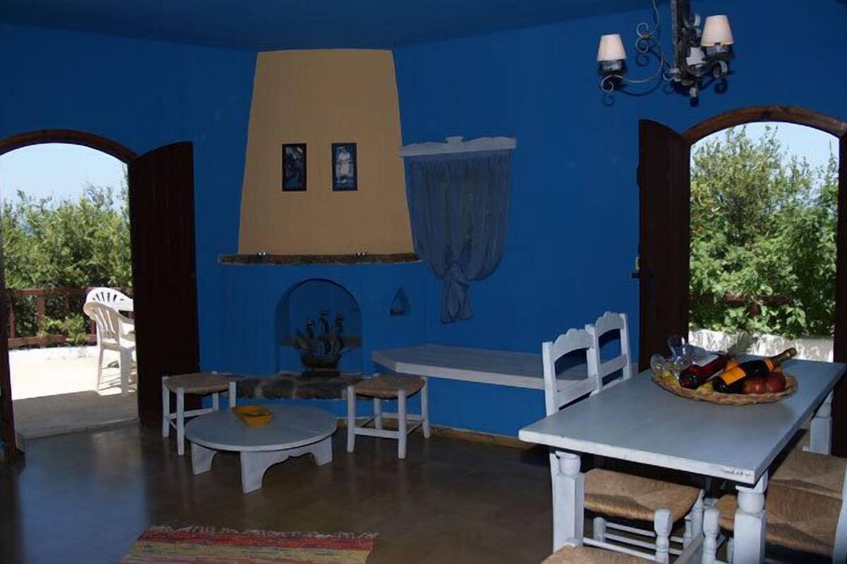 Ein Zimmer mit blauer Wand, einem weißen Tisch mit Obstschale und einer weißen Bank.