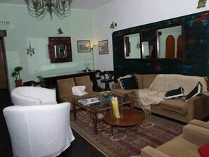 Uma sala de estar com sofá, poltronas, mesa de centro e espelho.
