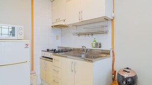 Una cocina compacta con armarios blancos, un microondas, una estufa y un fregadero.