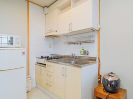 Una cocina compacta con armarios blancos, un microondas, una estufa y un fregadero.