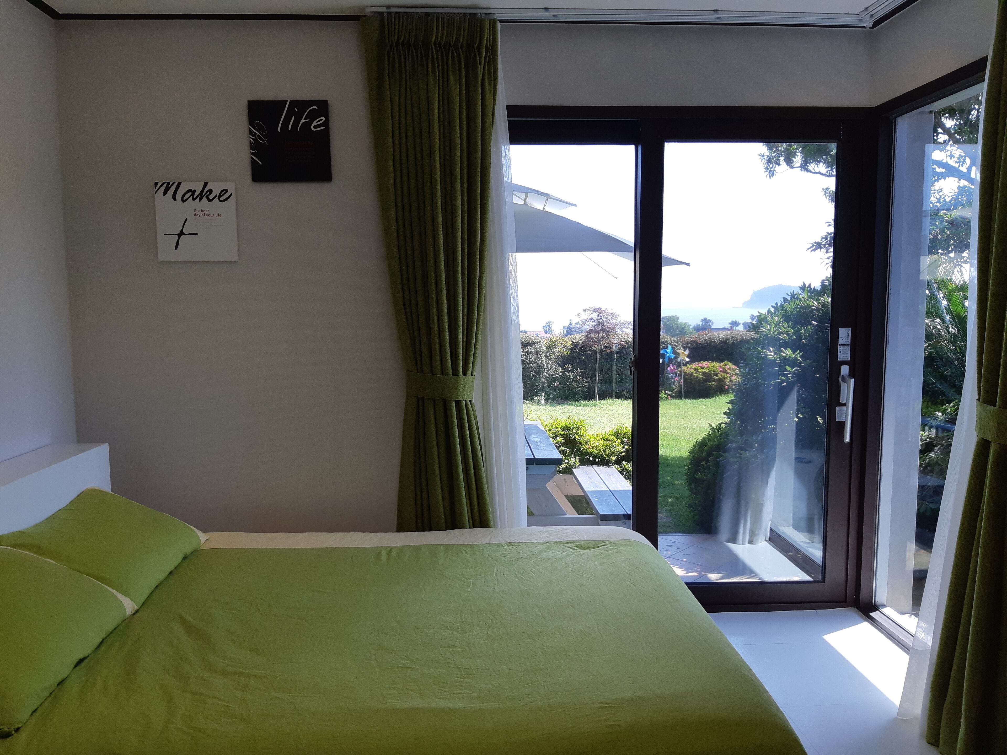 Une chambre à coucher avec un lit, une fenêtre et une vue sur un jardin.