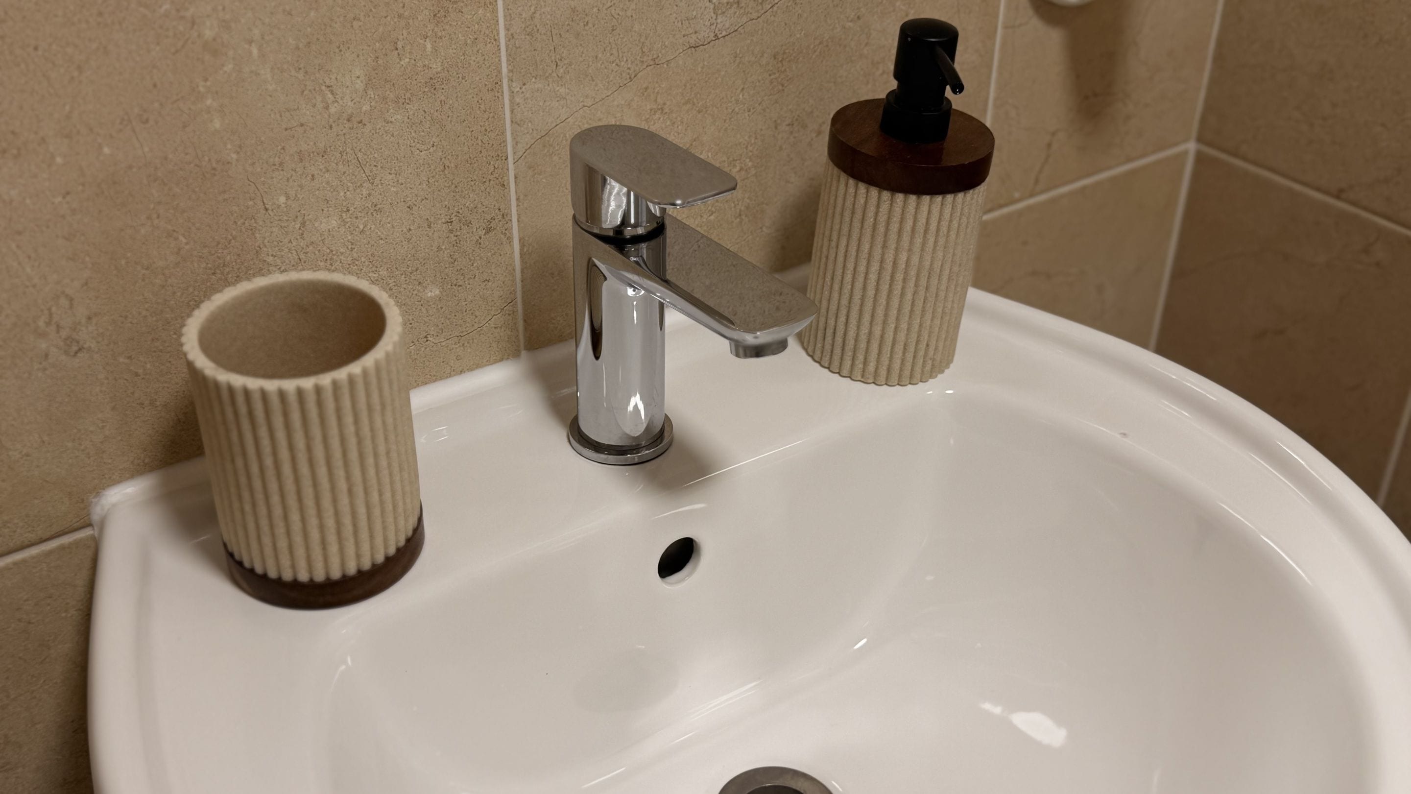 A bathroom sink with a chrome faucet, a soap dispenser, and a paper towel holder.