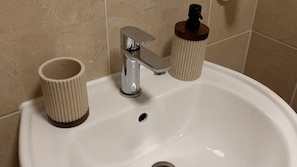 A bathroom sink with a chrome faucet, a soap dispenser, and a paper towel holder. - Waverley Guest House (Inverness)