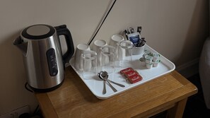 En köksbänk med en vattenkokare, måttkoppar, ett fat med köksredskap och förpackade livsmedel.