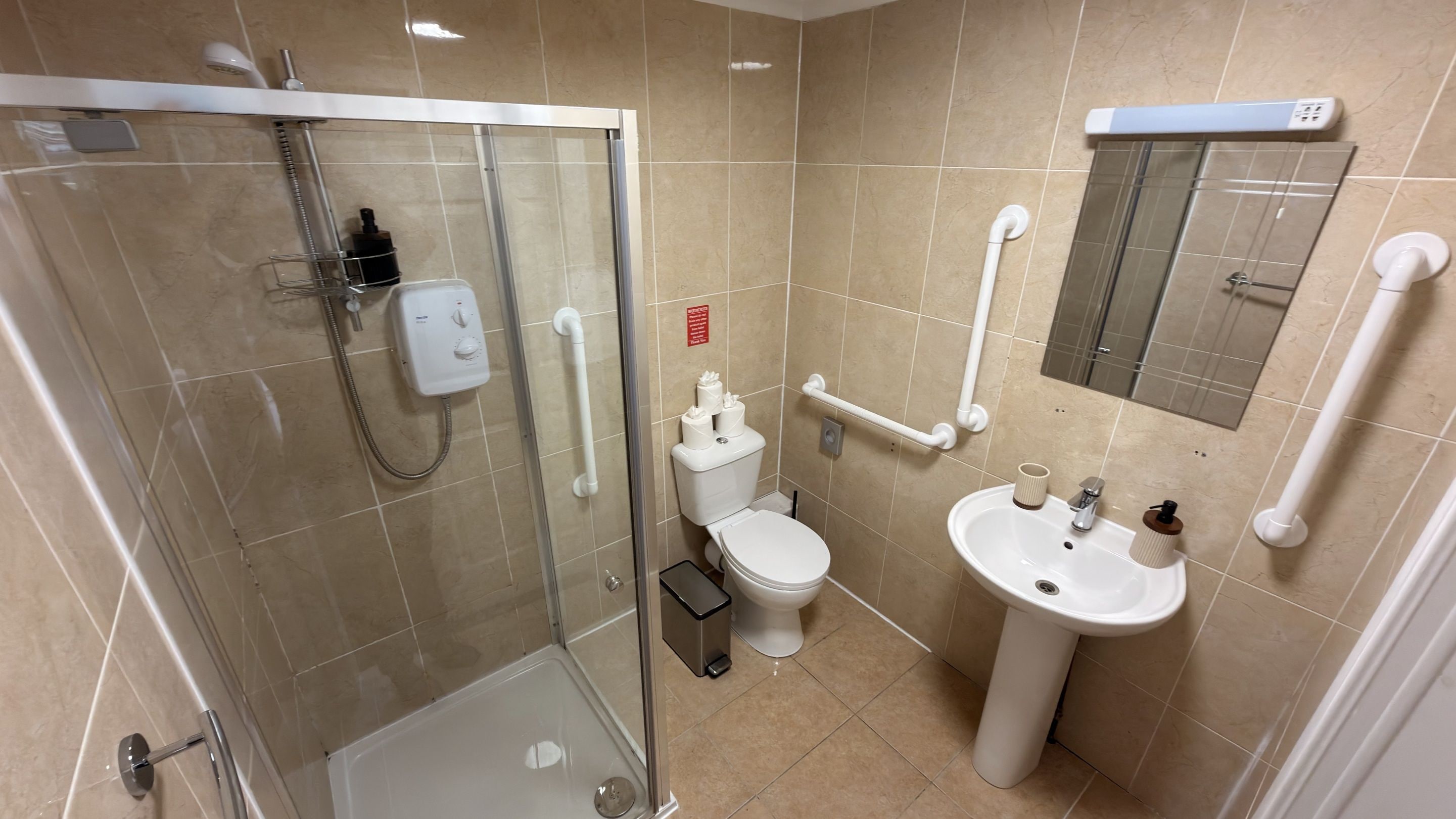 A modern bathroom with a glass-enclosed shower, a white toilet, and a pedestal sink.