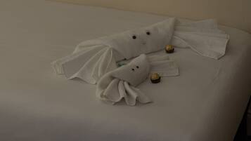 Una cama con dos toallas con forma de fantasma y un pequeño objeto envuelto.