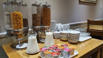 A breakfast buffet setup with cereal, milk, and yogurt containers.