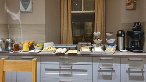 A breakfast buffet setup with various food items and a coffee machine. - Waverley Guest House (Inverness)