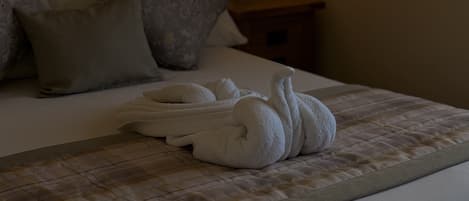A bed with a quilted bedspread, a neatly folded white towel, and a pillow.