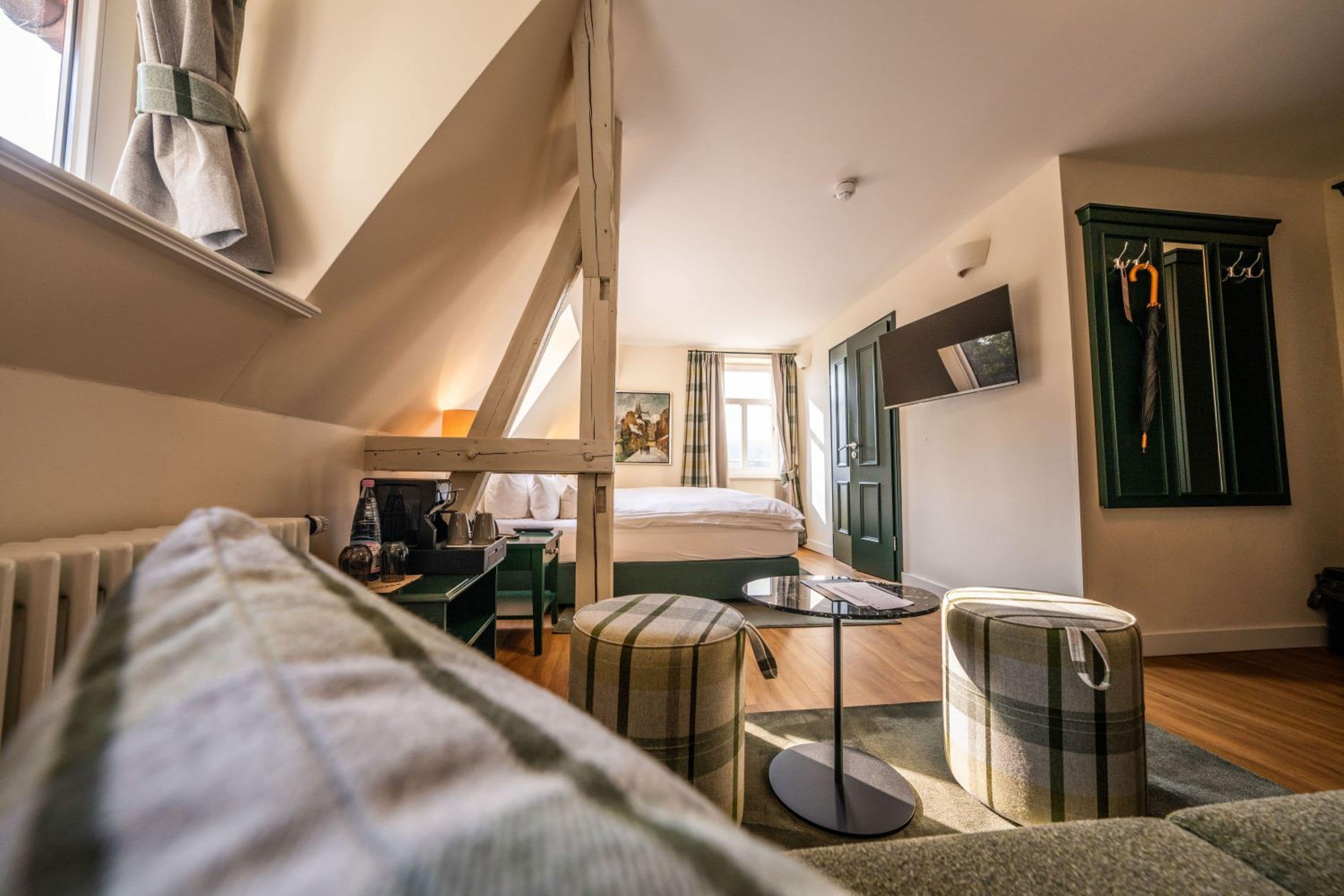 Une chambre confortable avec un lit, une petite table, une chaise, un radiateur et une fenêtre avec des rideaux.