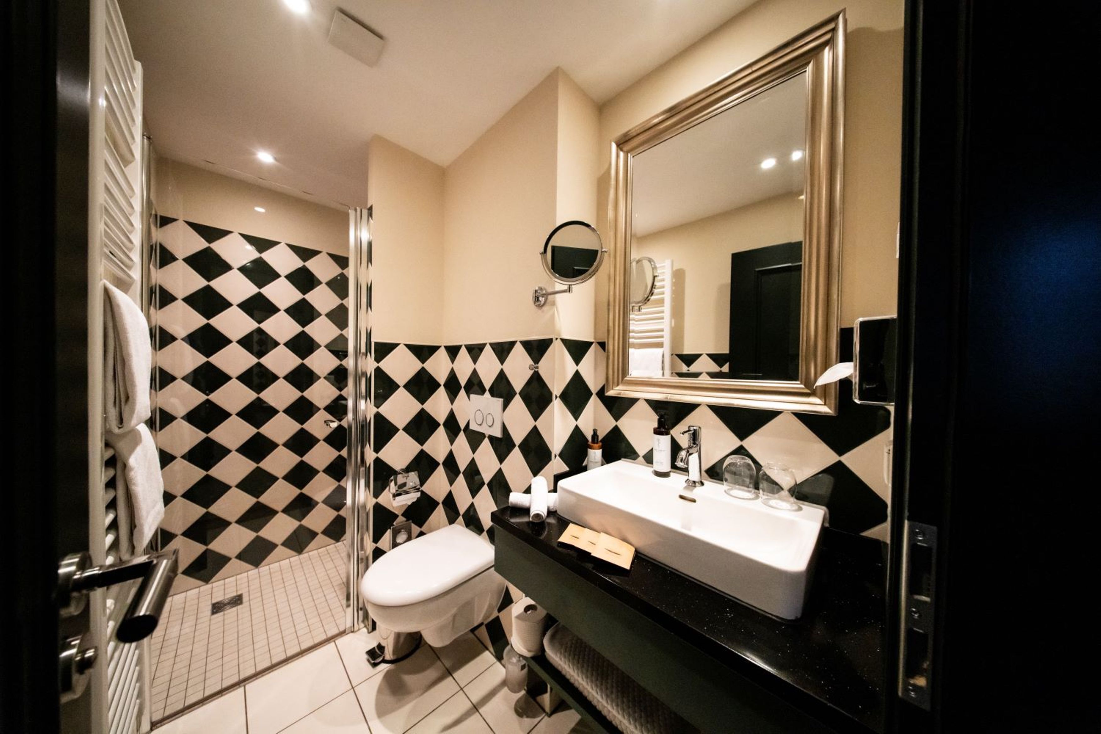 A modern bathroom with a black and white checkered floor, a white sink, and a large mirror.