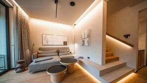 A modern living room with a sofa, two round coffee tables, and a staircase. - Hotel & Spa Suiten Freiwerk (Südharz)