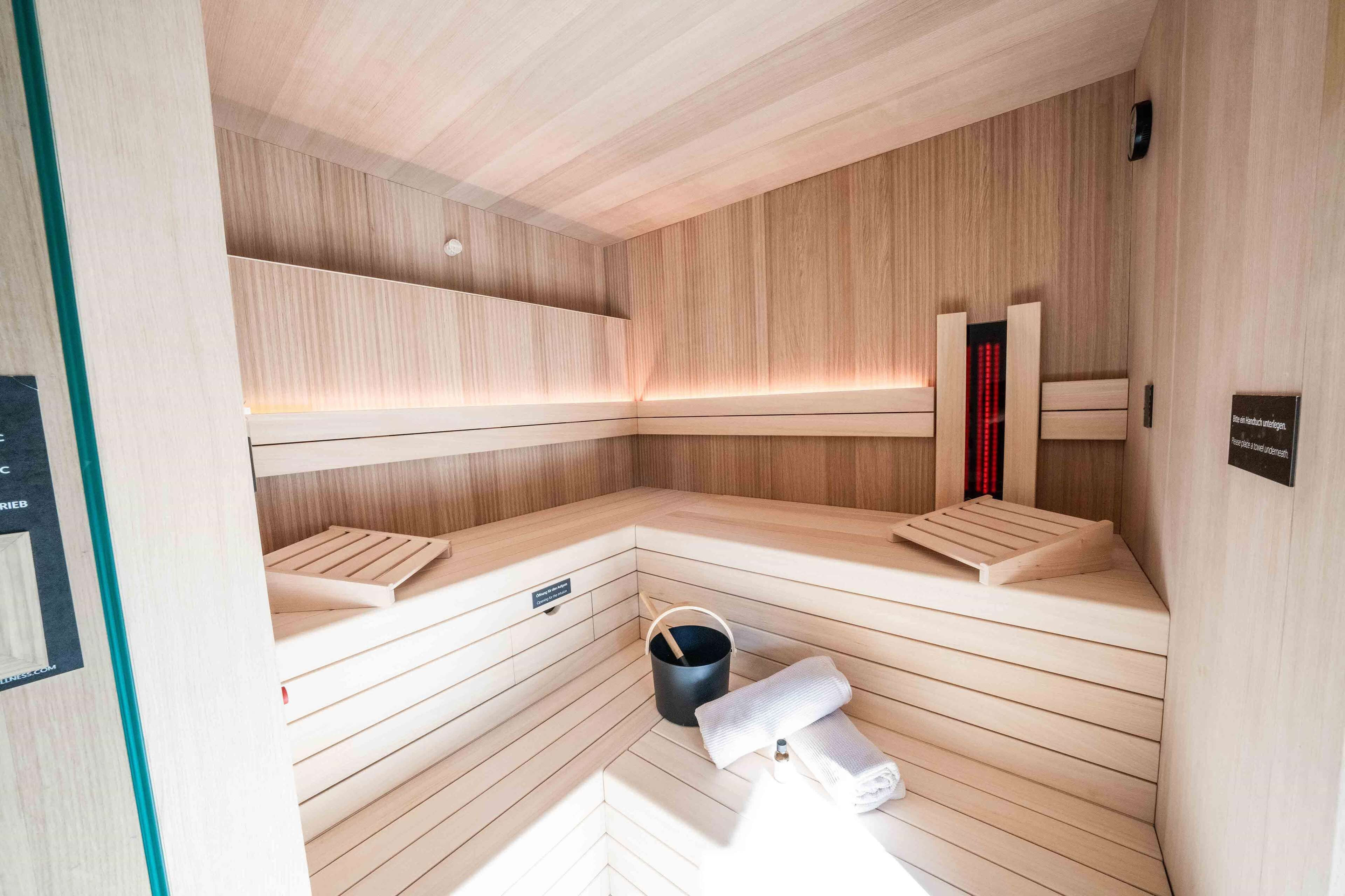 Eine Sauna mit Holzbänken, einem Handtuch und einem Eimer.