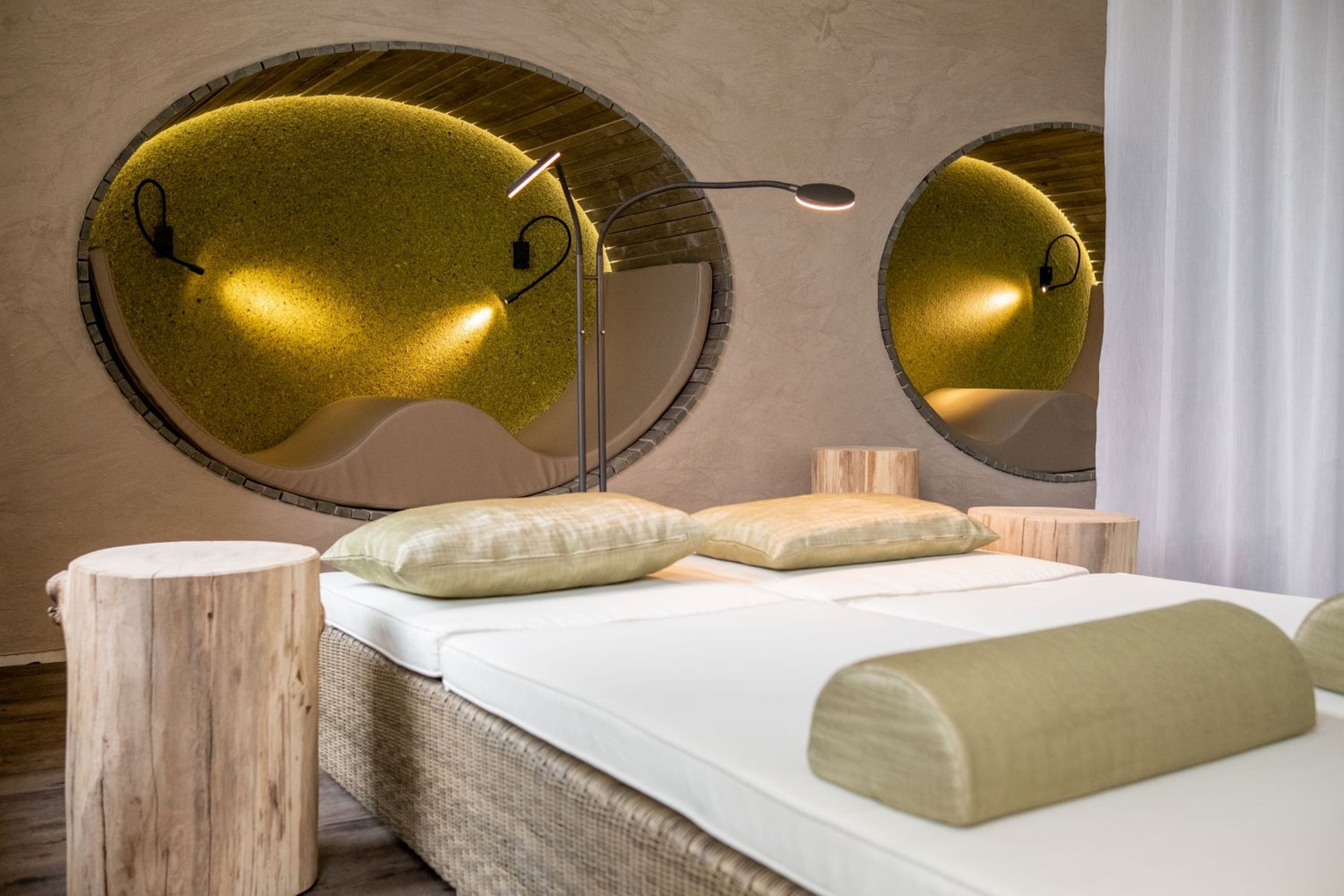 A modern bedroom with a circular mirror, a bed with white bedding, and wooden accents.