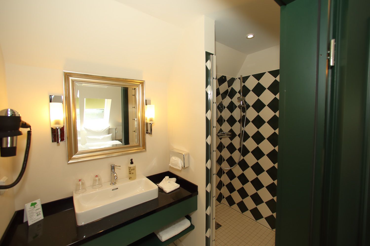 A hotel bathroom with a sink, mirror, and shower.