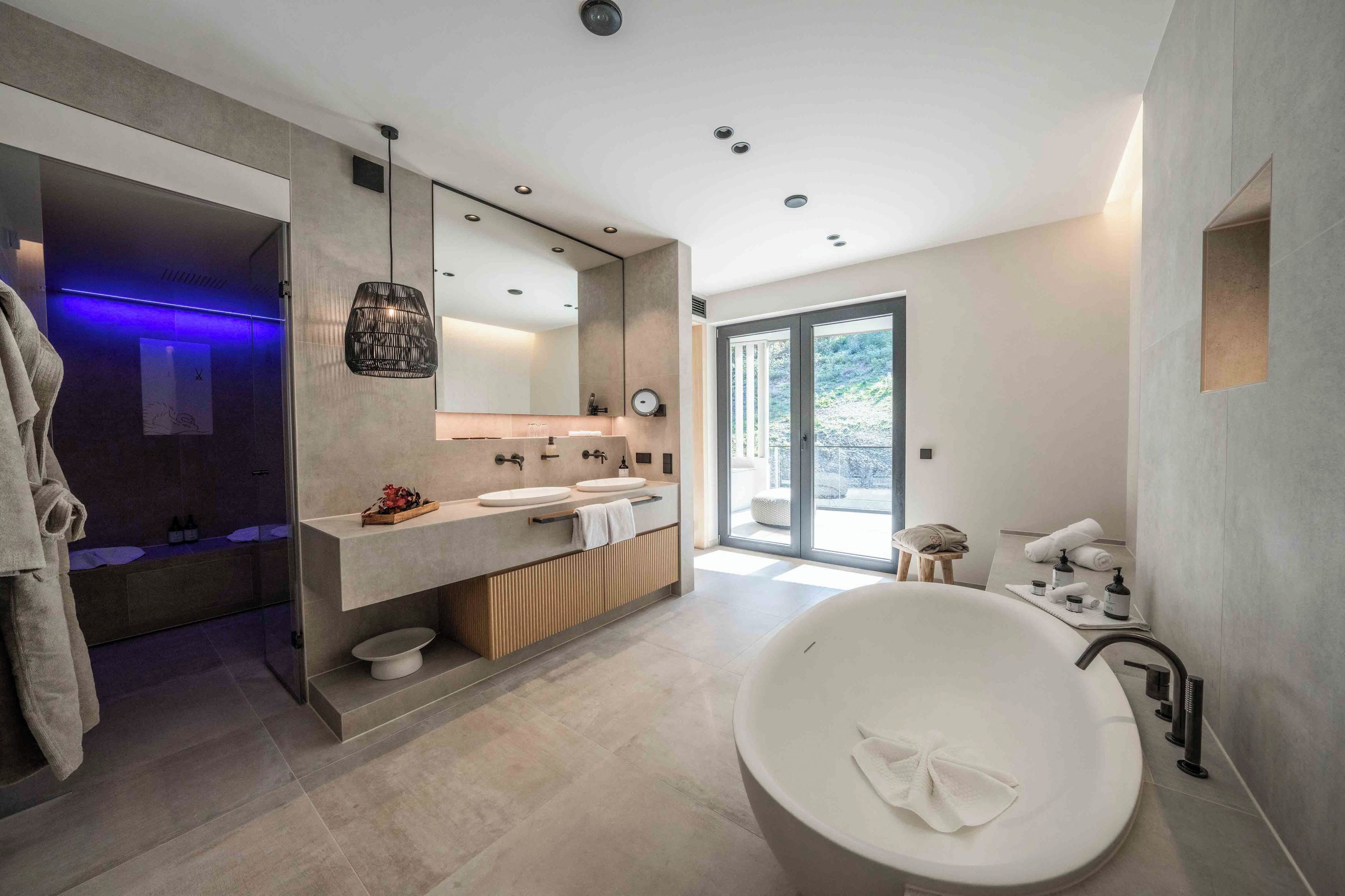 Un baño moderno con una bañera grande, dos lavamanos, un espejo y zona de ducha.