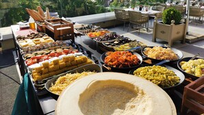 Una mesa de buffet con diversos alimentos y un tazón grande al frente.
